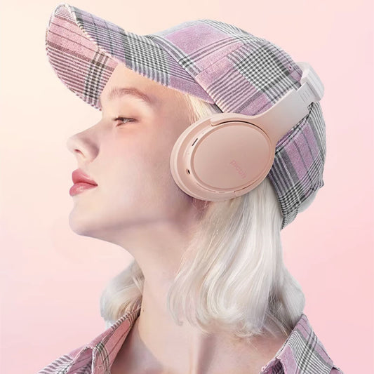 Person wearing pink headphones and a plaid hat on a pink background